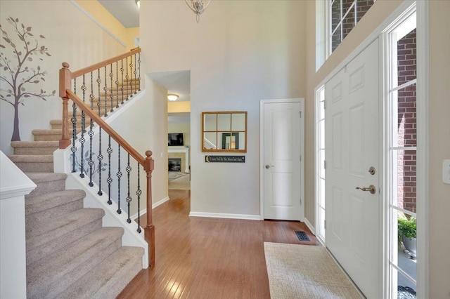 1060 Tinley Blvd, Oxford, MI 48371 - entryway featuring wood finished floors, stairs, a high ceiling, baseboards, and a glass covered fireplace