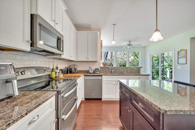 1060 Tinley Blvd, Oxford, MI 48371 - kitchen featuring appliances with stainless steel finishes, a sink, wood finished floors, backsplash, and white cabinetry