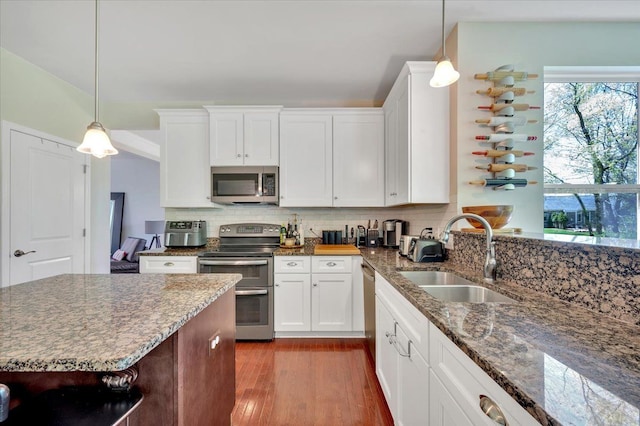 1060 Tinley Blvd, Oxford, MI 48371 - kitchen featuring stainless steel appliances, a sink, wood finished floors, light stone countertops, and tasteful backsplash