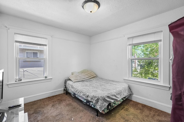 carpeted bedroom with a textured ceiling and baseboards