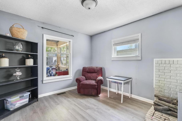living area featuring wood finished floors, a textured ceiling, and baseboards