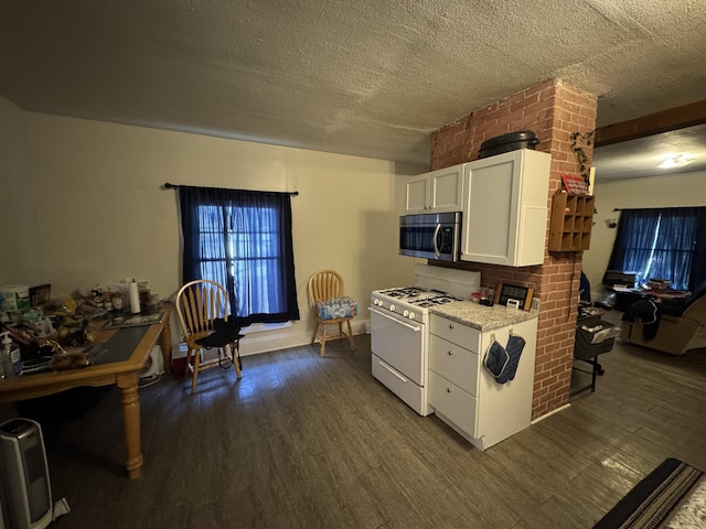127 N Camburn St, Stanton, MI 48888 - kitchen with white gas range, stainless steel microwave, dark wood finished floors, white cabinets, and a textured ceiling