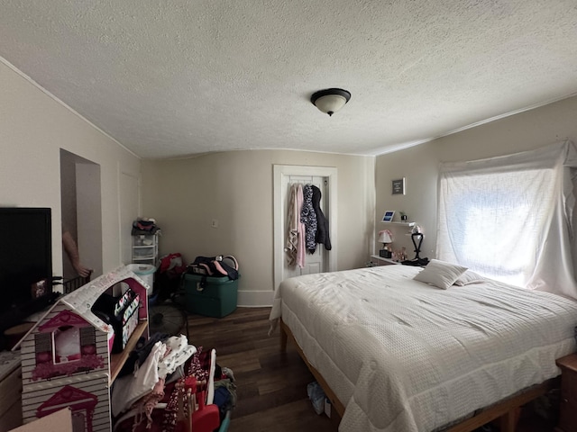 bedroom with wood finished floors, a textured ceiling, a closet, and baseboards