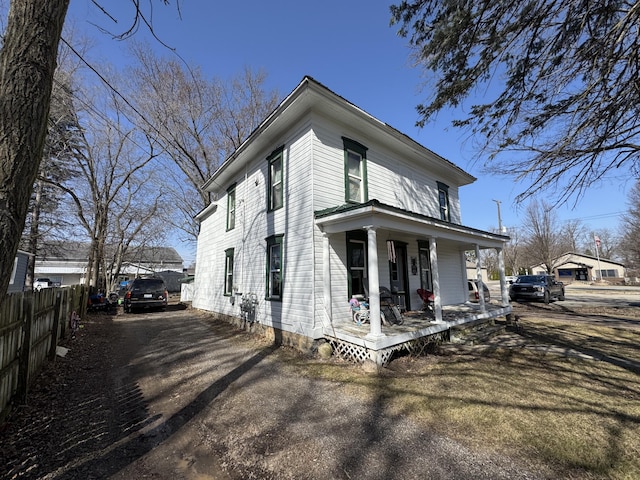 view of home's exterior featuring a porch and fence