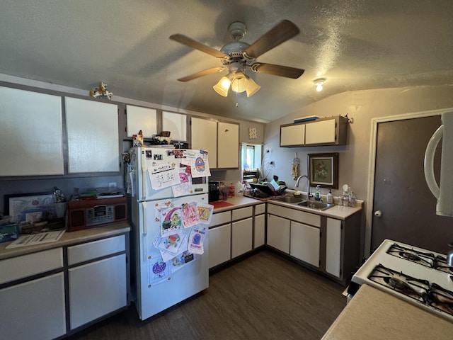 kitchen featuring freestanding refrigerator, a sink, dark wood-type flooring, lofted ceiling, and light countertops