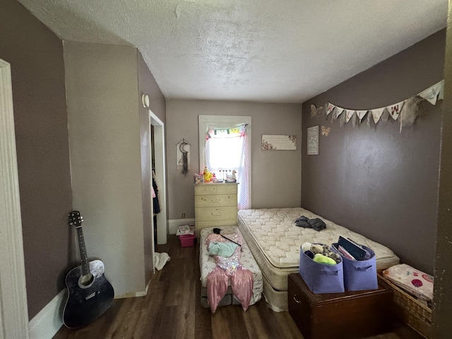 bedroom featuring wood finished floors, a textured ceiling, and baseboards
