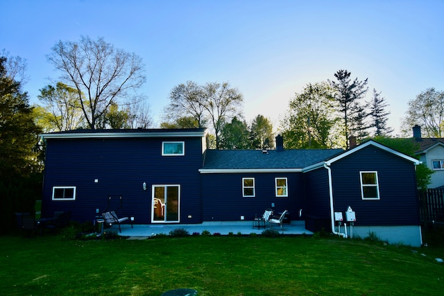 rear view of house with a patio area, a lawn, and a chimney