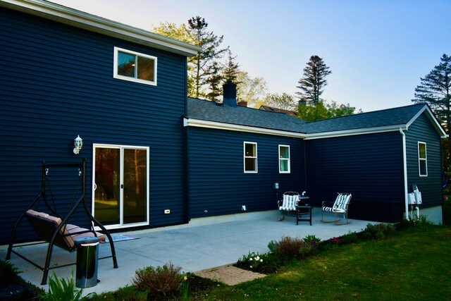 back of house featuring a chimney, a patio area, and a yard