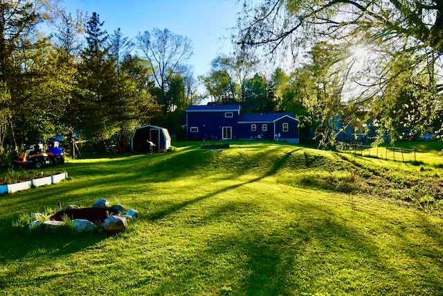 view of community featuring a storage shed, an outdoor structure, a lawn, and view of scattered trees