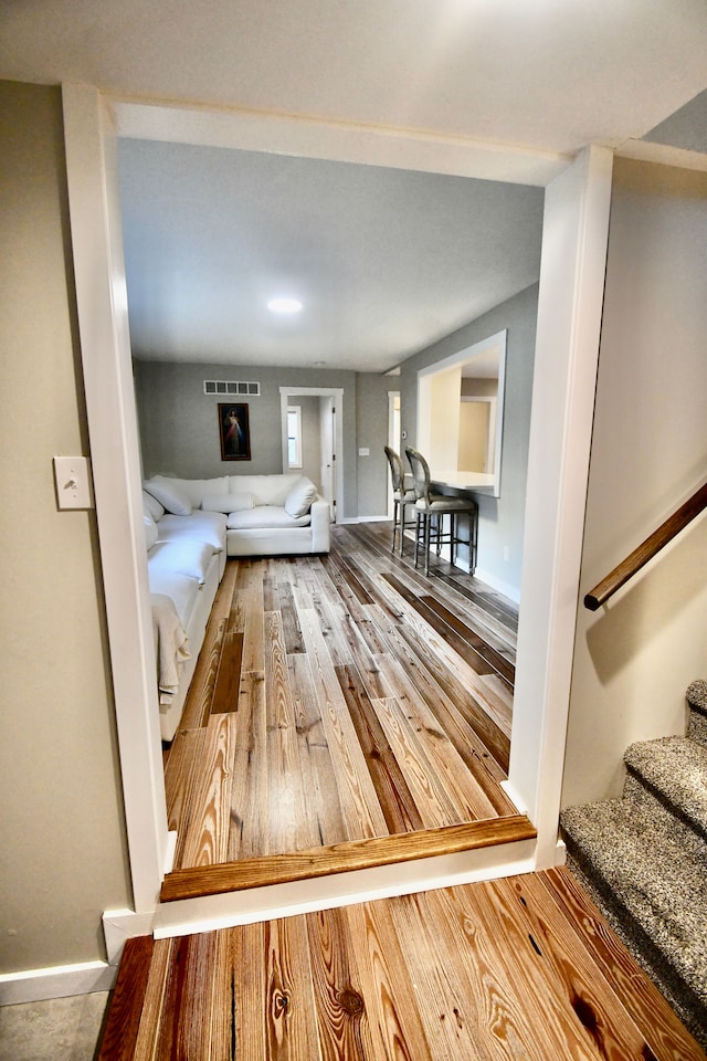 unfurnished living room featuring wood finished floors, stairs, and baseboards