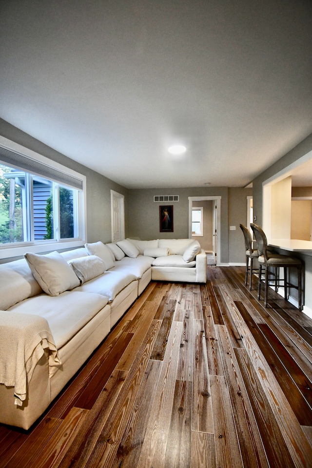 living room with dark wood-style floors, plenty of natural light, and baseboards