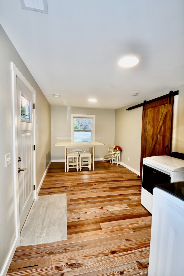dining area featuring light wood finished floors, baseboards, and a barn door