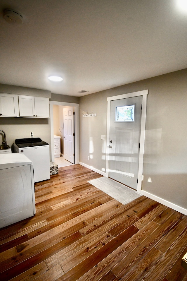 interior space featuring hardwood / wood-style flooring, washer and dryer, cabinet space, and baseboards