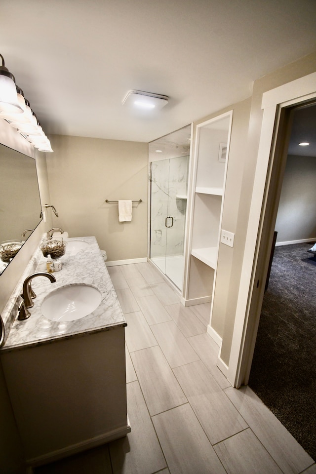 full bath with a shower stall, baseboards, and double vanity