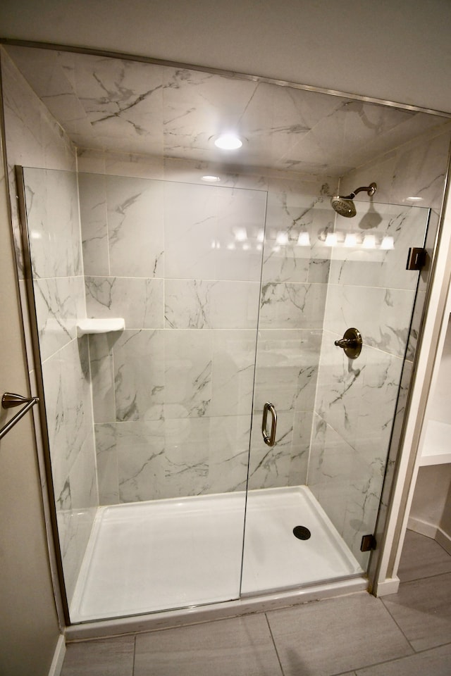 full bathroom featuring a marble finish shower and baseboards