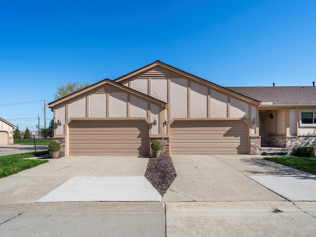 view of front facade with concrete driveway, an attached garage, stucco siding, and brick siding