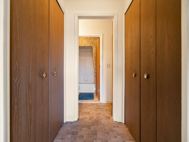 hall featuring stone finish floors and baseboards