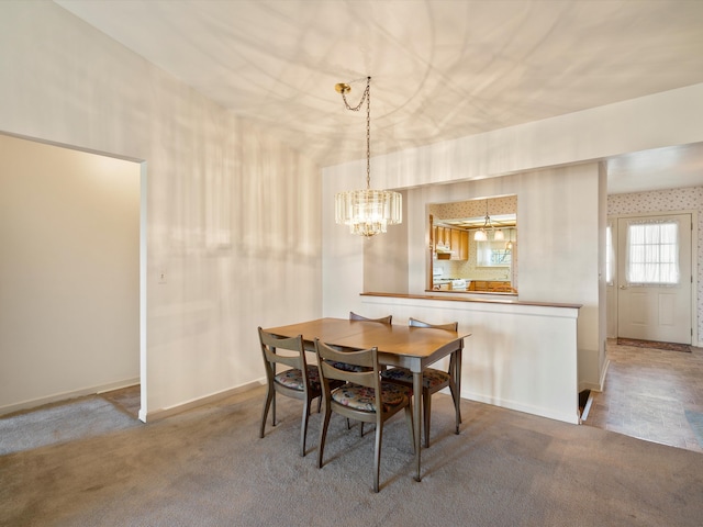 carpeted dining area with a chandelier and baseboards