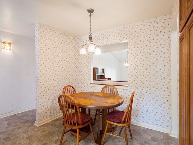 dining area featuring wallpapered walls, a chandelier, and baseboards