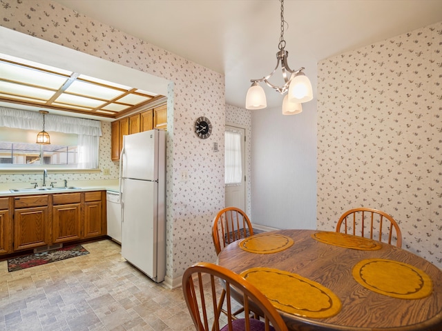 dining space with wallpapered walls, stone finish flooring, baseboards, and a chandelier