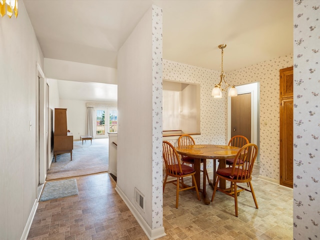 dining space featuring baseboards, a chandelier, and wallpapered walls
