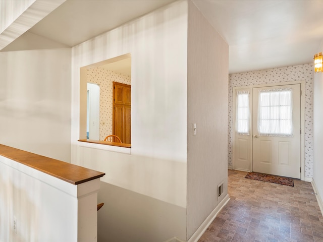 foyer with wallpapered walls and baseboards
