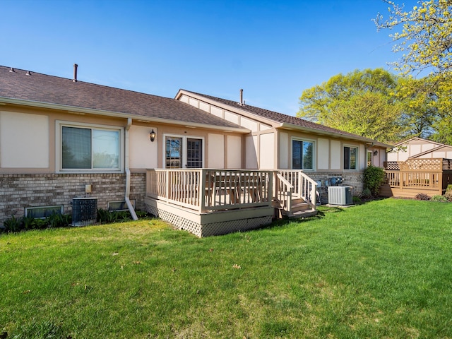 back of house with stucco siding, central AC, a wooden deck, and a yard