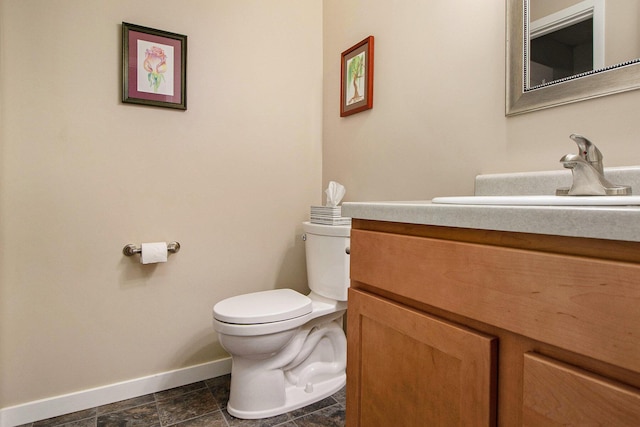 bathroom with baseboards, toilet, and vanity