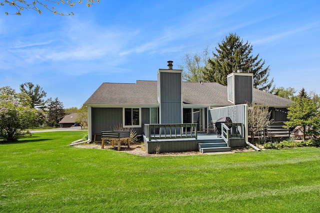 back of property featuring a chimney, a lawn, a wooden deck, and roof with shingles