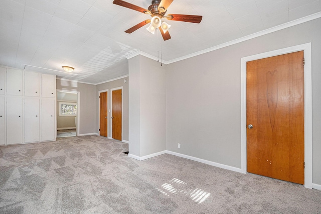 unfurnished bedroom with carpet flooring, baseboards, ornamental molding, and ceiling fan