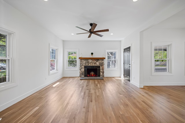 unfurnished living room featuring light wood-style floors, a ceiling fan, a stone fireplace, baseboards, and recessed lighting