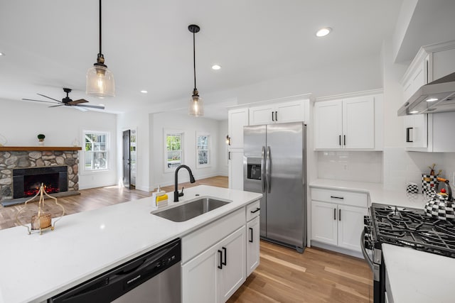 kitchen with stainless steel appliances, a sink, light wood-style floors, open floor plan, and light countertops