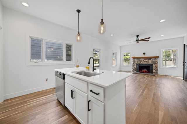kitchen with a sink, stainless steel dishwasher, pendant lighting, ceiling fan, and light wood-style floors