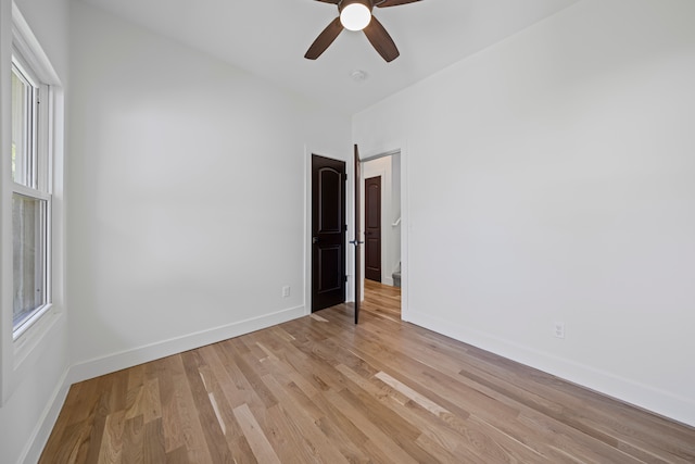 empty room featuring light wood finished floors, baseboards, and a ceiling fan