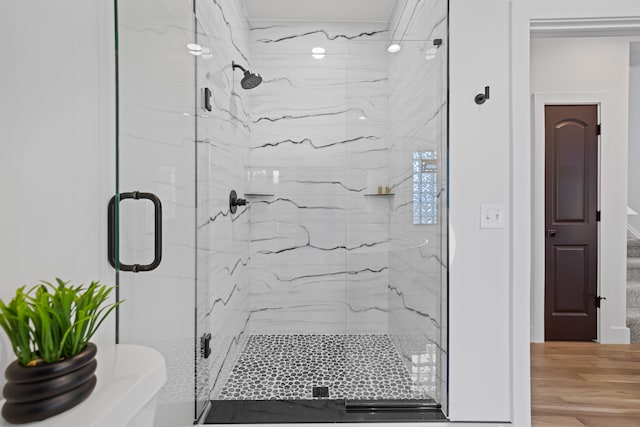 bathroom featuring a marble finish shower and wood finished floors