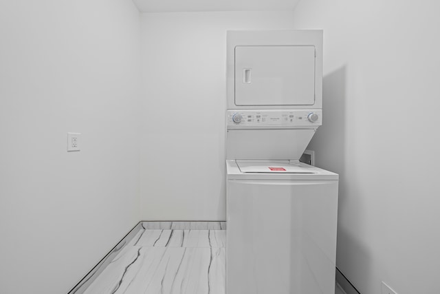 washroom with stacked washer and clothes dryer and baseboards
