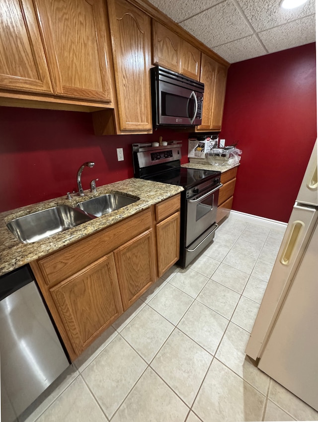 41315 Carriage Hill Dr, Novi, MI 48375 - kitchen with stainless steel appliances, a sink, light tile patterned flooring, brown cabinetry, and light stone countertops
