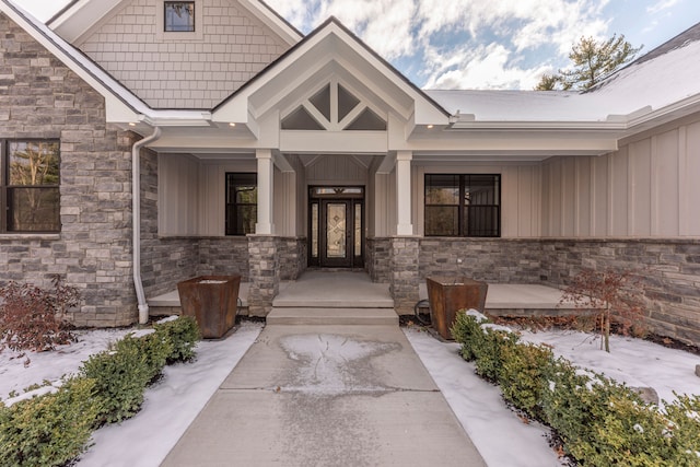 5535 W Huron River Dr, Dexter, MI 48130 - snow covered property entrance with stone siding, board and batten siding, and covered porch