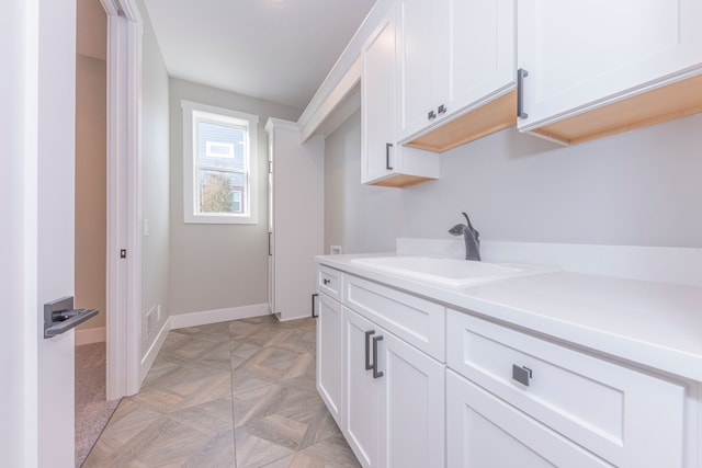 5535 W Huron River Dr, Dexter, MI 48130 - kitchen featuring a sink, white cabinetry, light countertops, and baseboards