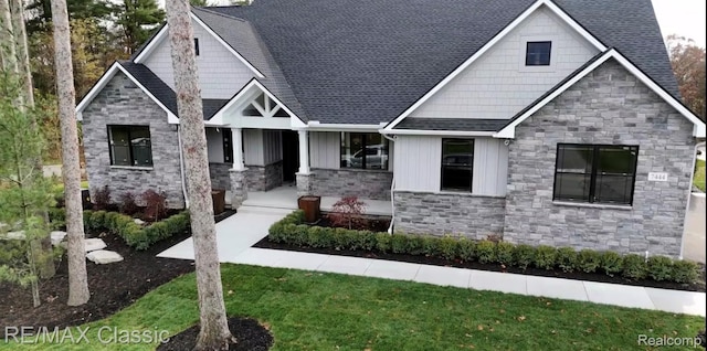 5535 W Huron River Dr, Dexter, MI 48130 - craftsman house featuring stone siding, a porch, board and batten siding, a shingled roof, and a front yard