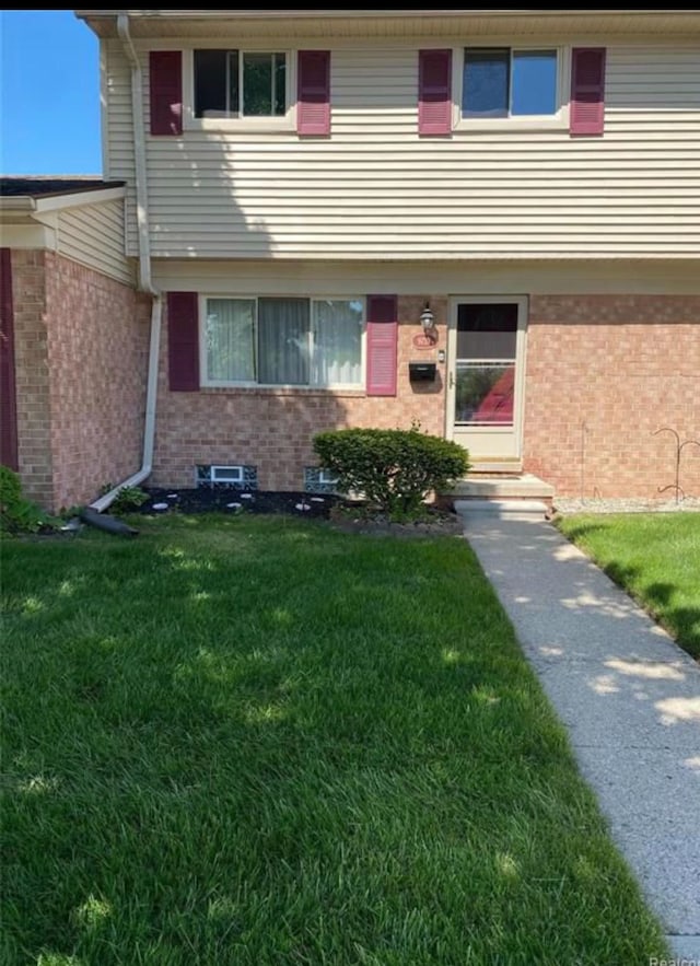 entrance to property featuring brick siding and a yard