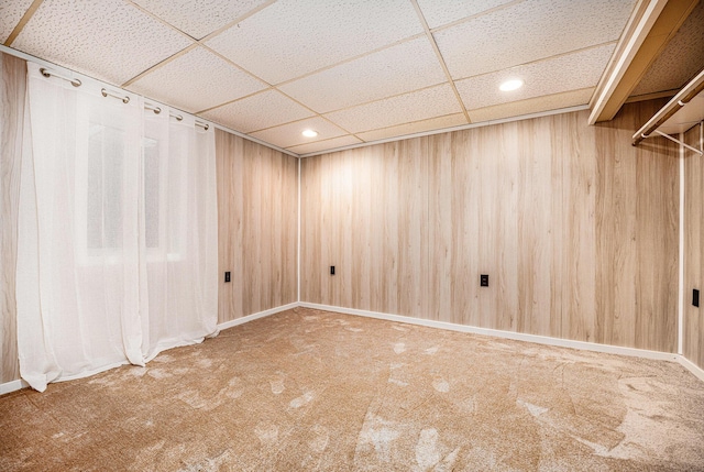 carpeted empty room featuring recessed lighting, a drop ceiling, and wood walls