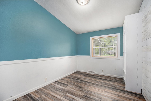 spare room with vaulted ceiling, wood finished floors, and baseboards