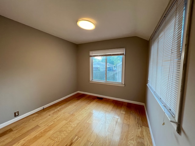 unfurnished room with light wood-style floors, baseboards, and lofted ceiling