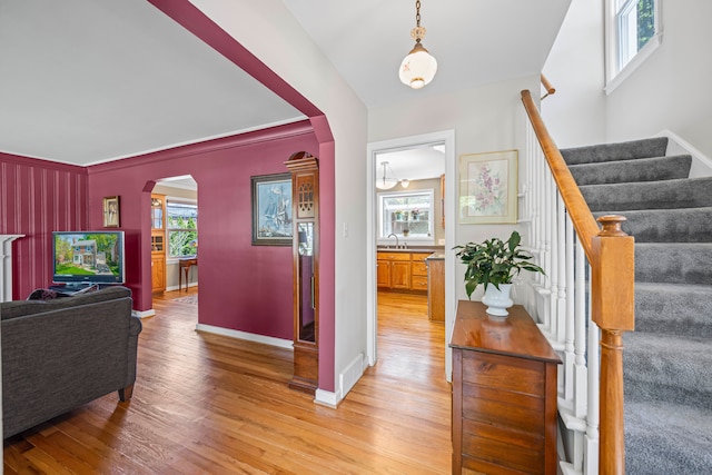 foyer entrance featuring arched walkways, light wood-type flooring, and healthy amount of natural light