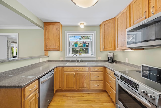 kitchen with appliances with stainless steel finishes, a sink, light wood-type flooring, a peninsula, and ornamental molding