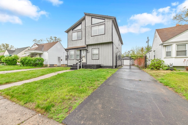 view of front of home with a front lawn, driveway, an outdoor structure, and a detached garage