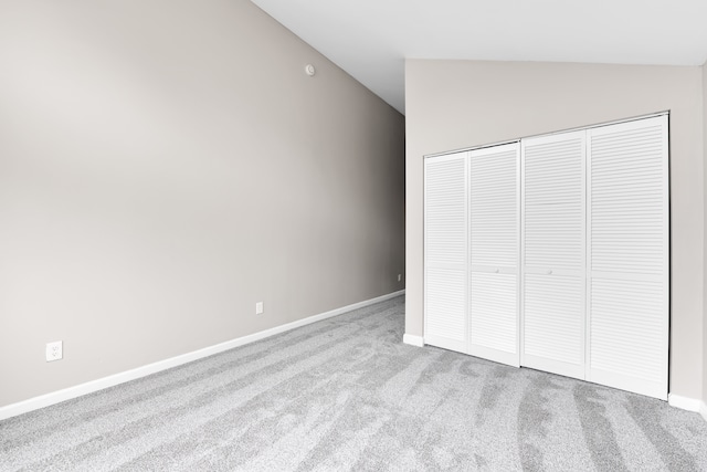 unfurnished bedroom with vaulted ceiling, carpet flooring, baseboards, and a closet