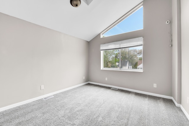 spare room featuring carpet flooring, vaulted ceiling, and baseboards