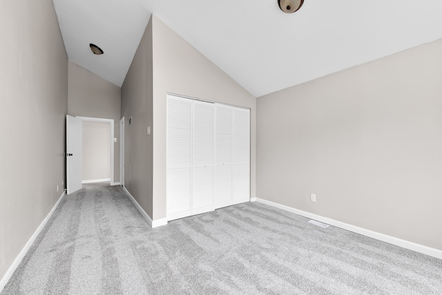 unfurnished bedroom featuring carpet floors, high vaulted ceiling, baseboards, and a closet
